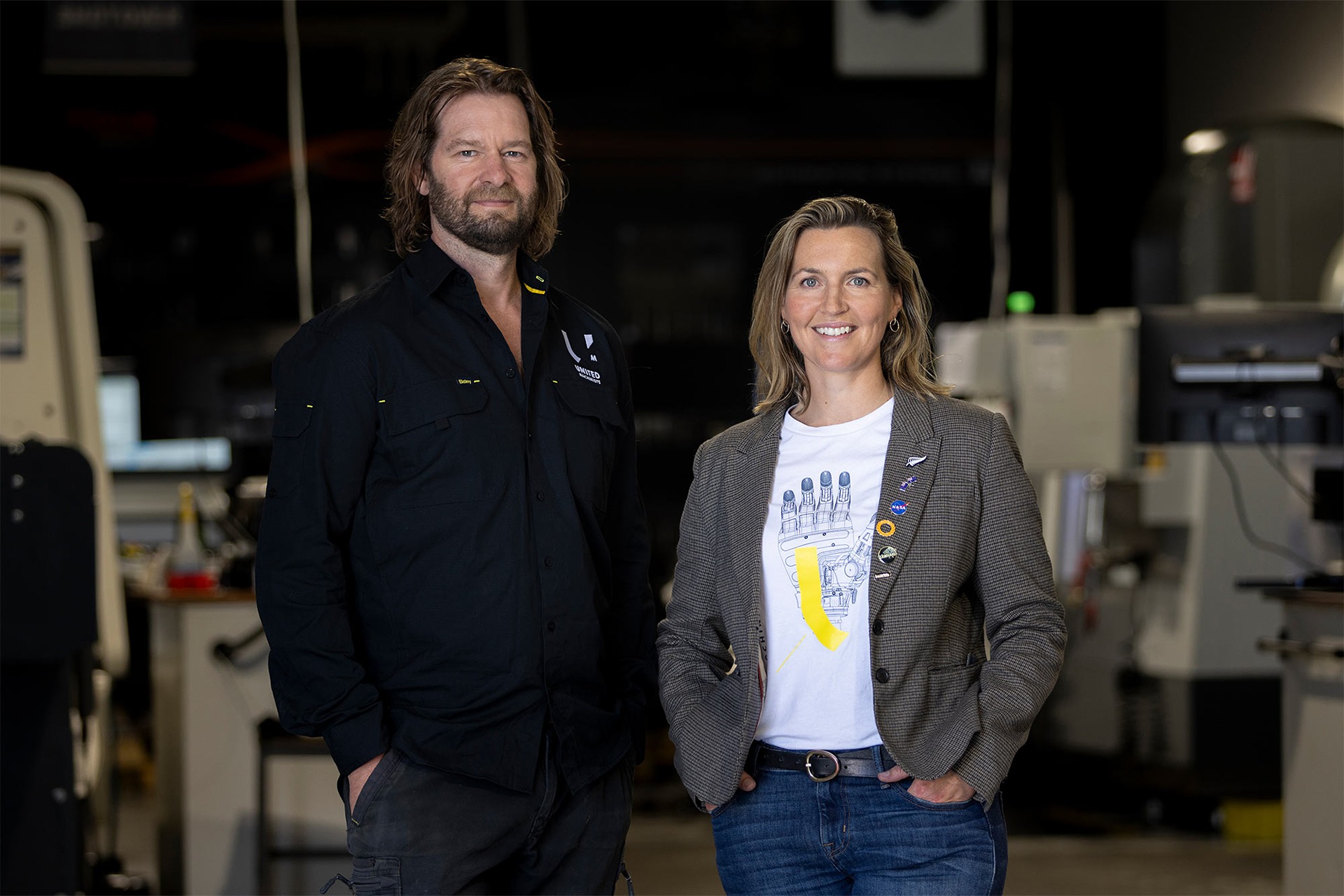 Alex and Sarah Ramsay, owners of United Machinists, standing inside their precision machining workshop